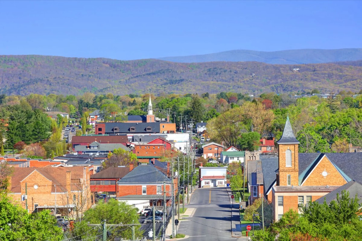 Downtown Blacksburg from above: brick buildings and church steeples along Main Street, with mountains behind